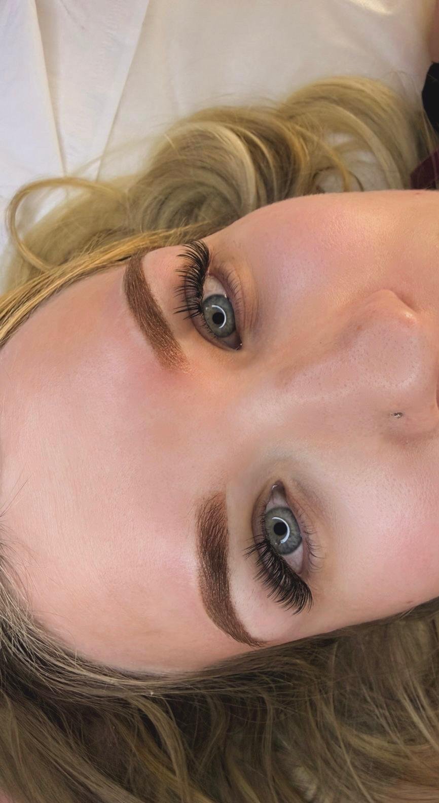 Definierte, natürlich geformte Augenbrauen mit Wimpernverlängerung bei einer blonden Kundin